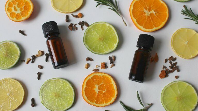 vials of essential oils among slices of citrus and sprigs of rosemary